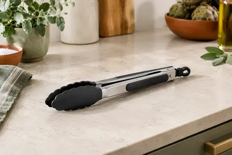 Pince de cuisine iNeibo en acier inoxydable poli et silicone noir posée sur un plan de travail clair.